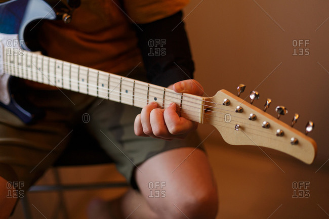 Close up of young man practicing his electric guitar