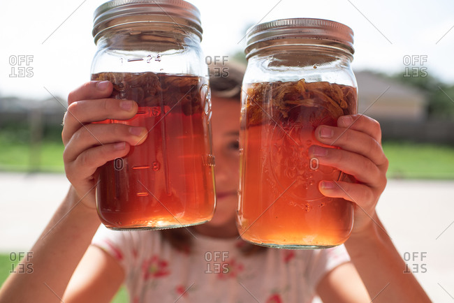 Girl holding two jars of sun tea