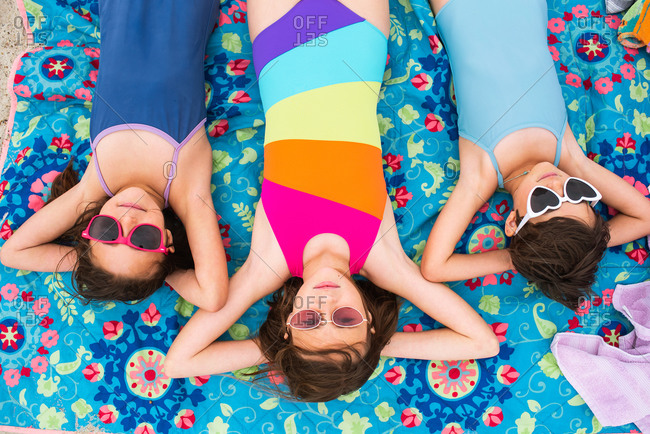 Overhead view of three young girls sunbathing on a beach