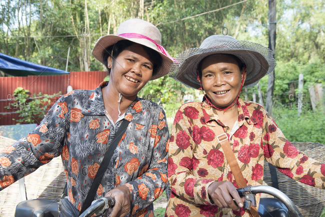 November 20, 2014: Two local women with their bicycles smiling together in Siem Reap, Cambodia, Indochina, Southeast Asia, Asia