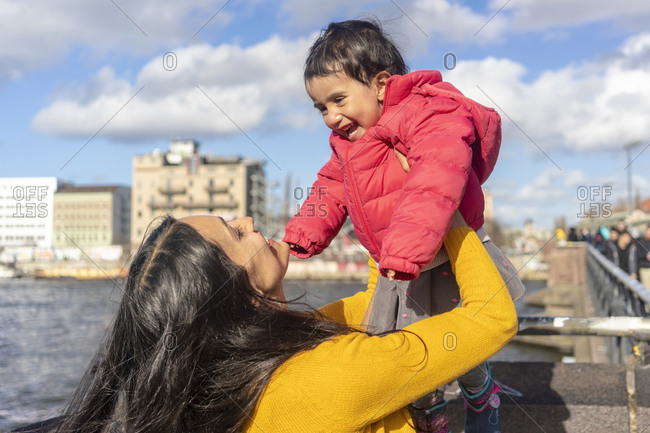 Mother lifting daughter in mid air by river, Berlin, Germany