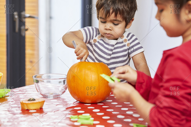 Boy gutting pumpkin in kitchen