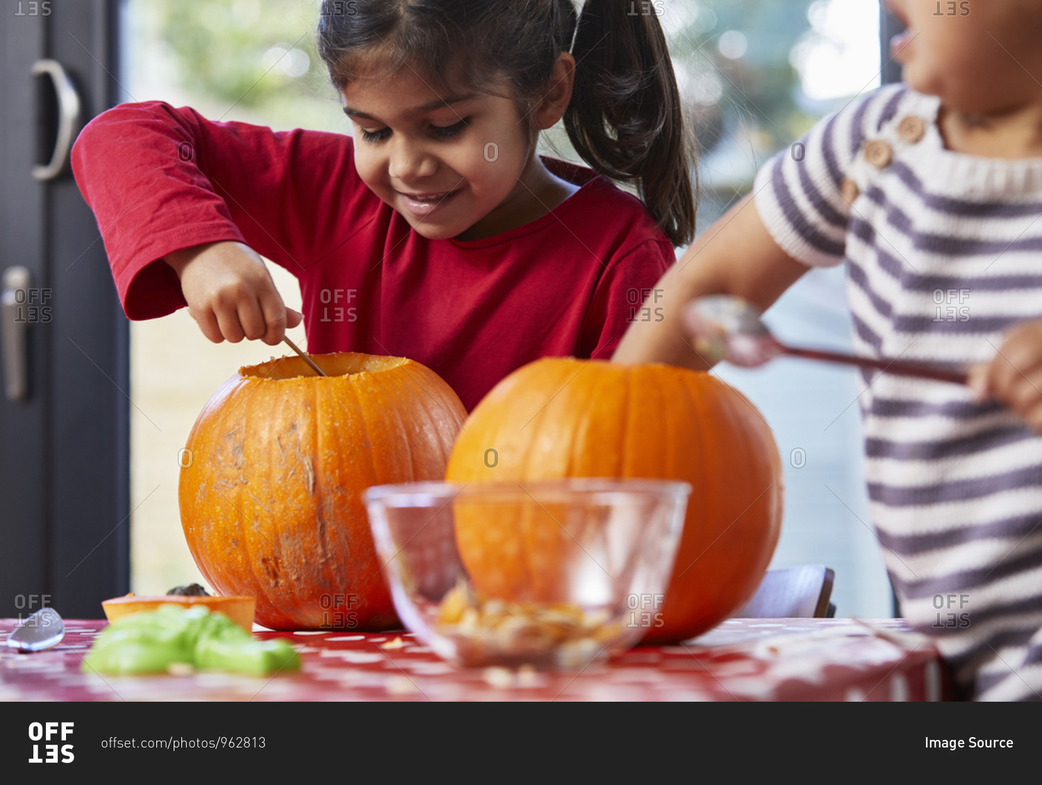 Children gutting pumpkin in kitchen