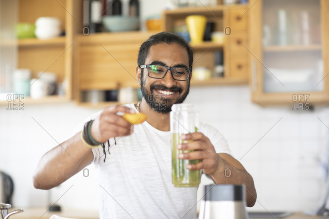 Man making green juice in kitchen