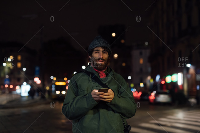 Bearded young man using smartphone on street