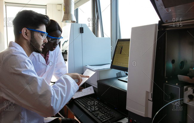 Young female and male scientists reading paperwork in laboratory