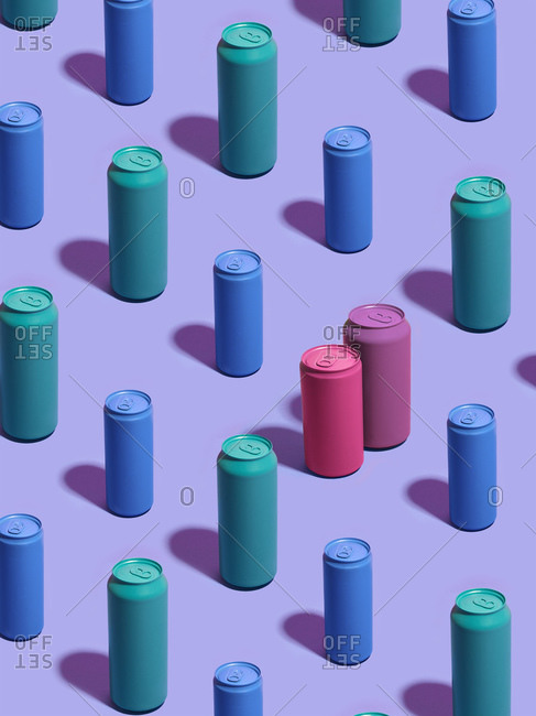 Still life of turquoise and blue drink cans in diagonal rows, with pink and purple drink cans standing out from the crowd on purple background