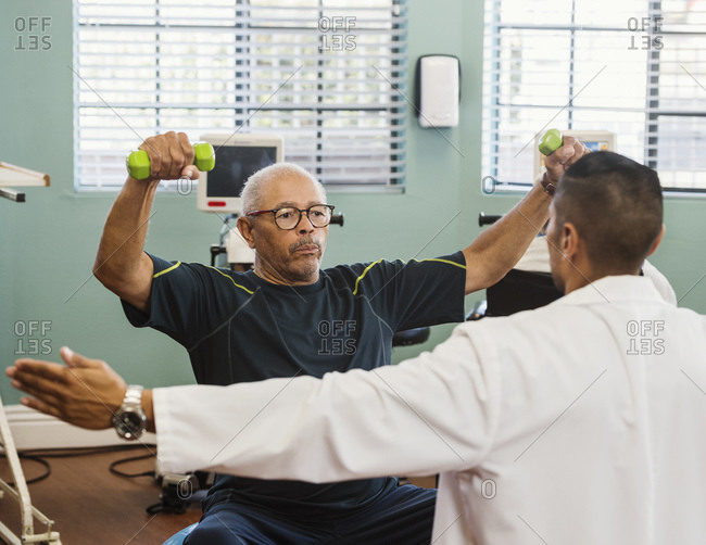 Senior man exercising with therapist during physical therapy