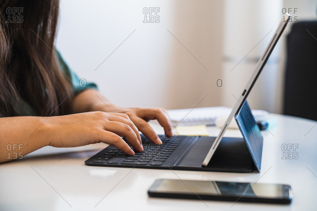 Close up of a woman's hands typing on the keyboard of her hybrid tablet, adapting to the new normal after coronavirus crisis