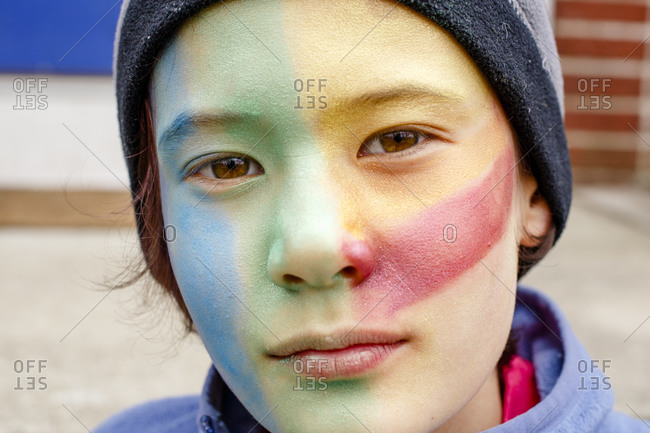 Portrait of beautiful boy with colorful face paint and direct gaze