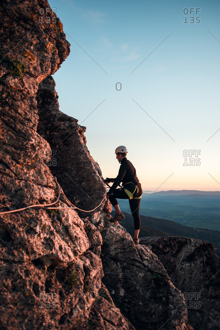 Climber woman with helmet and harness examining path