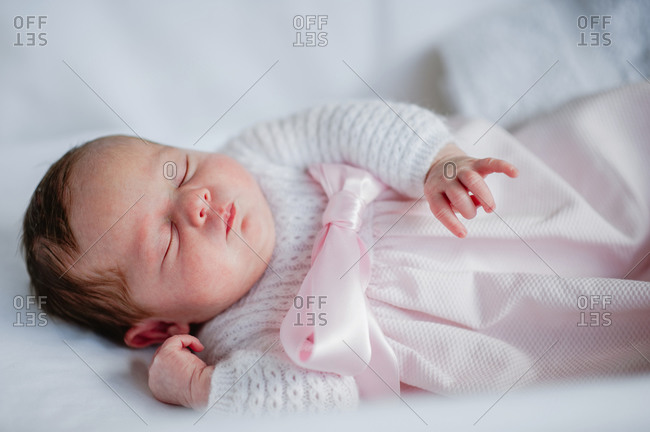 High angle of adorable baby girl in cozy dress lying in cot while sleeping