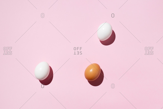 Top view of seamless background of brown and white eggs placed on pink surface in studio