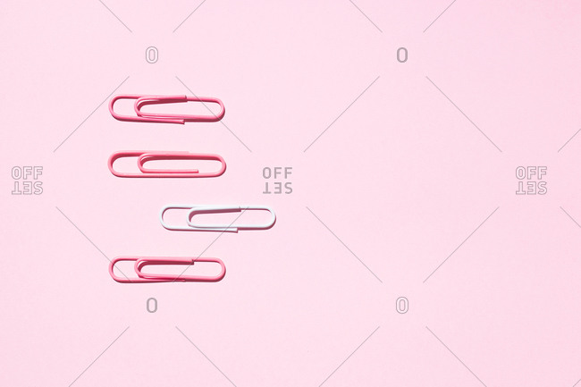 Top view of white and pink paper clips arranged on colorful background showing concept of uniqueness