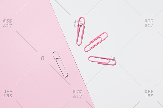 Top view of white and pink paper clips arranged on colorful background showing concept of uniqueness