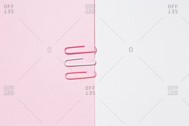 Top view of white and pink paper clips arranged on colorful background showing concept of uniqueness