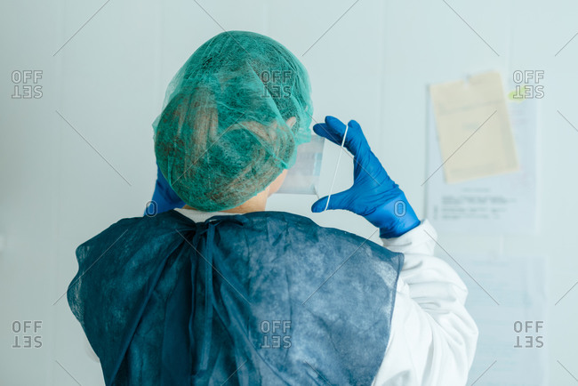 Young female medic in protective wear and mask putting on goggles while working in hospital during coronavirus pandemic