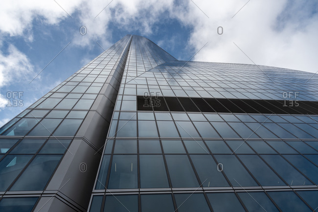November 27, 2019: Low angle of contemporary high rise building facade with glass exterior under white cloudy sky in modern city district