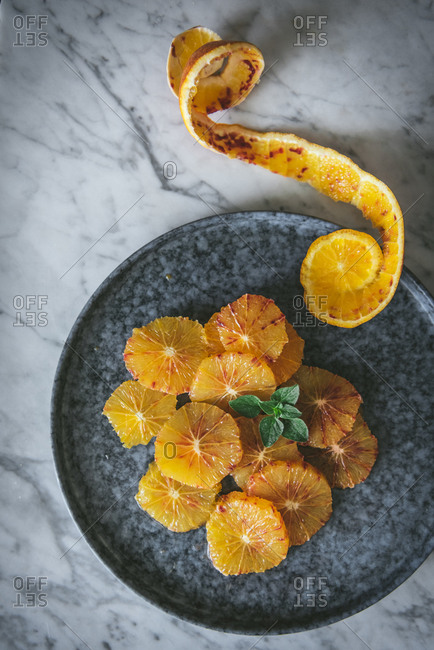 Top view of fresh citrus slices arranged on dish with orange peel and placed on table in kitchen