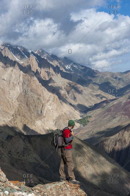 A trekker takes a break and admires the dramatic scenery from the top of the Dung Dung La during the Hidden valleys trek in Ladakh in India