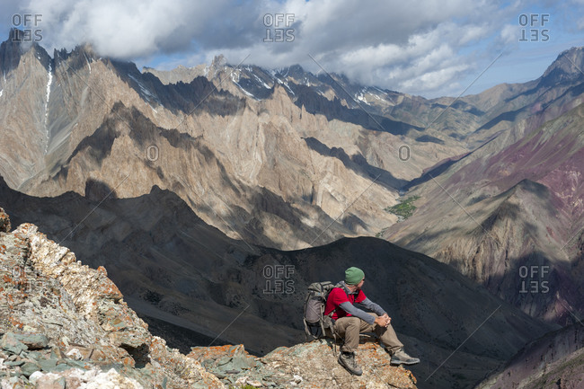 A trekker takes a break and admires the dramatic scenery from the top of the Dung Dung La during the Hidden valleys trek in Ladakh in India