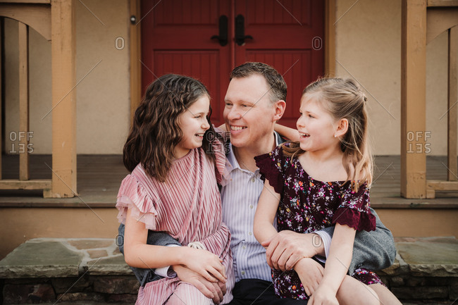 Father posing with daughters before a father-daughter dance