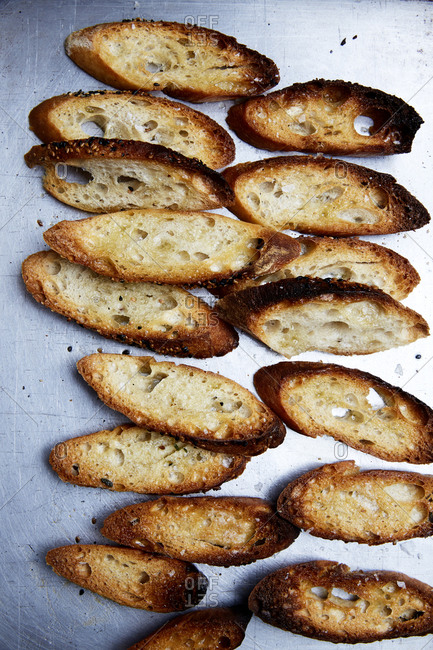 Sliced and toasted baguette on a roasting tray