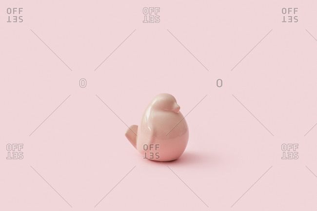 Wonderful small statuette of ceramic pink colored bird for decoration interior on the same color background, copy space.