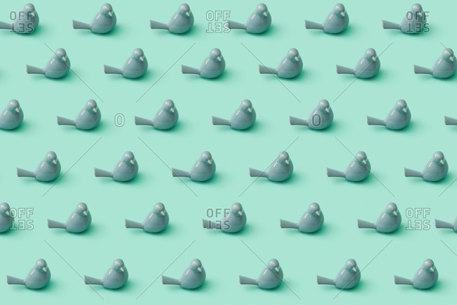 Creative horizontal pattern from beautiful small porcelain grey birds on a pastel turquoise background. Interior decoration concept.