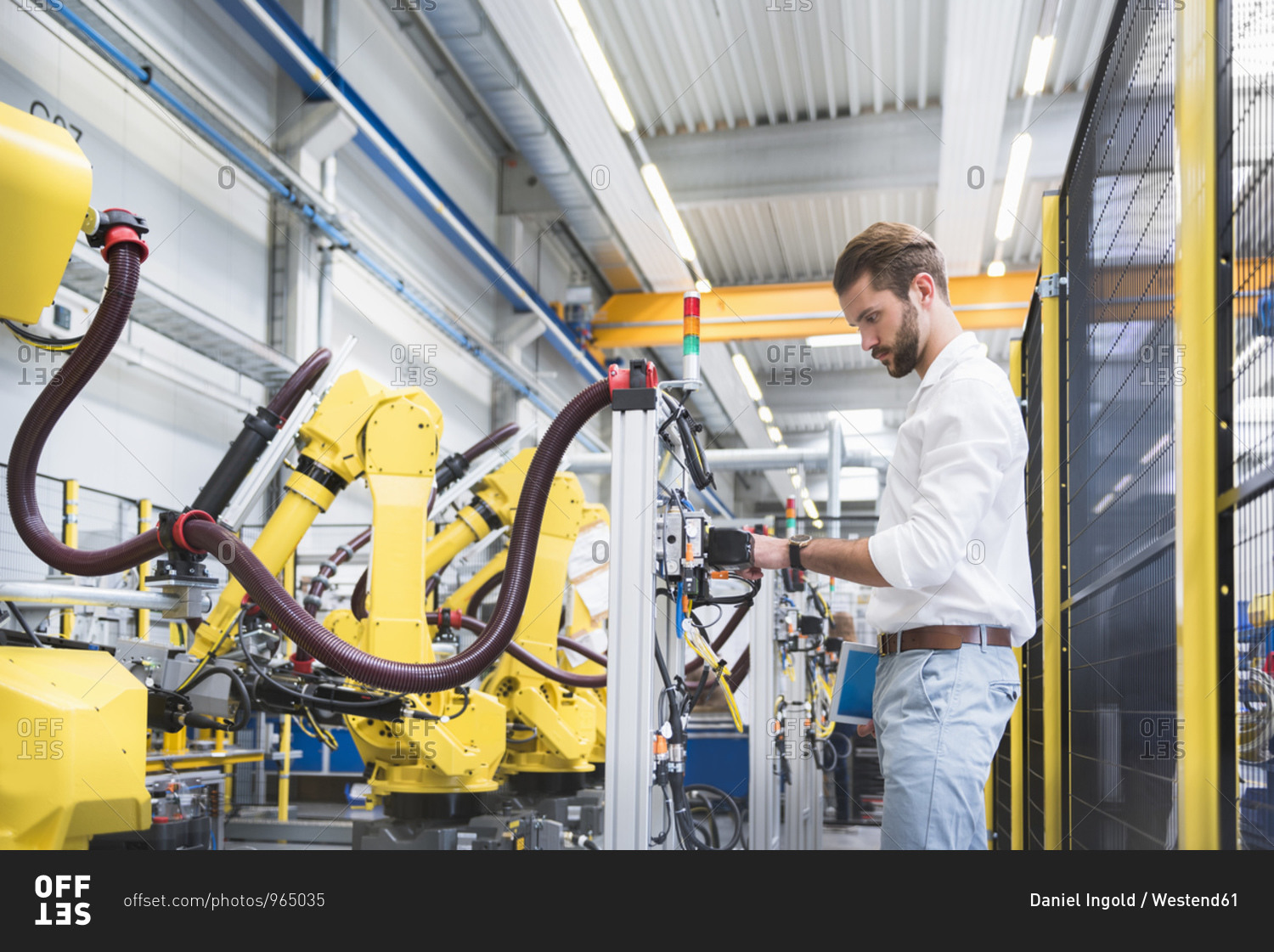 Side view of confident robotics expert examining machinery in factory