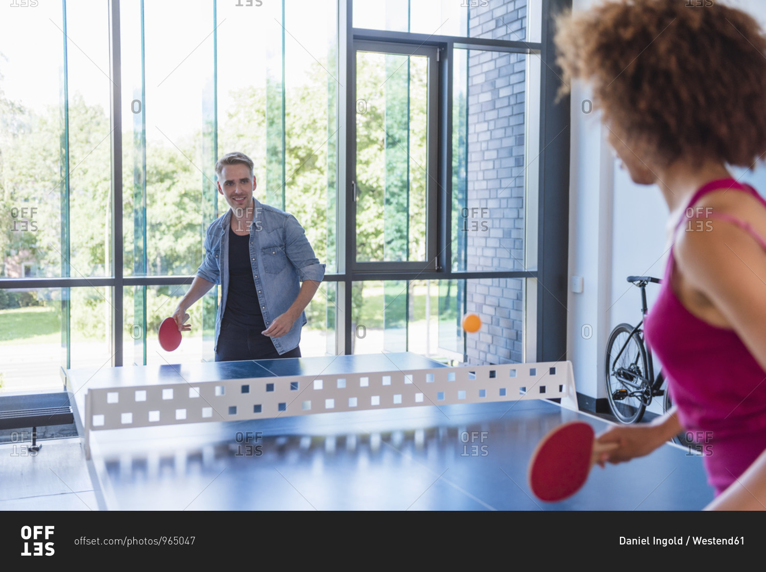 Young business people playing table tennis in loft office