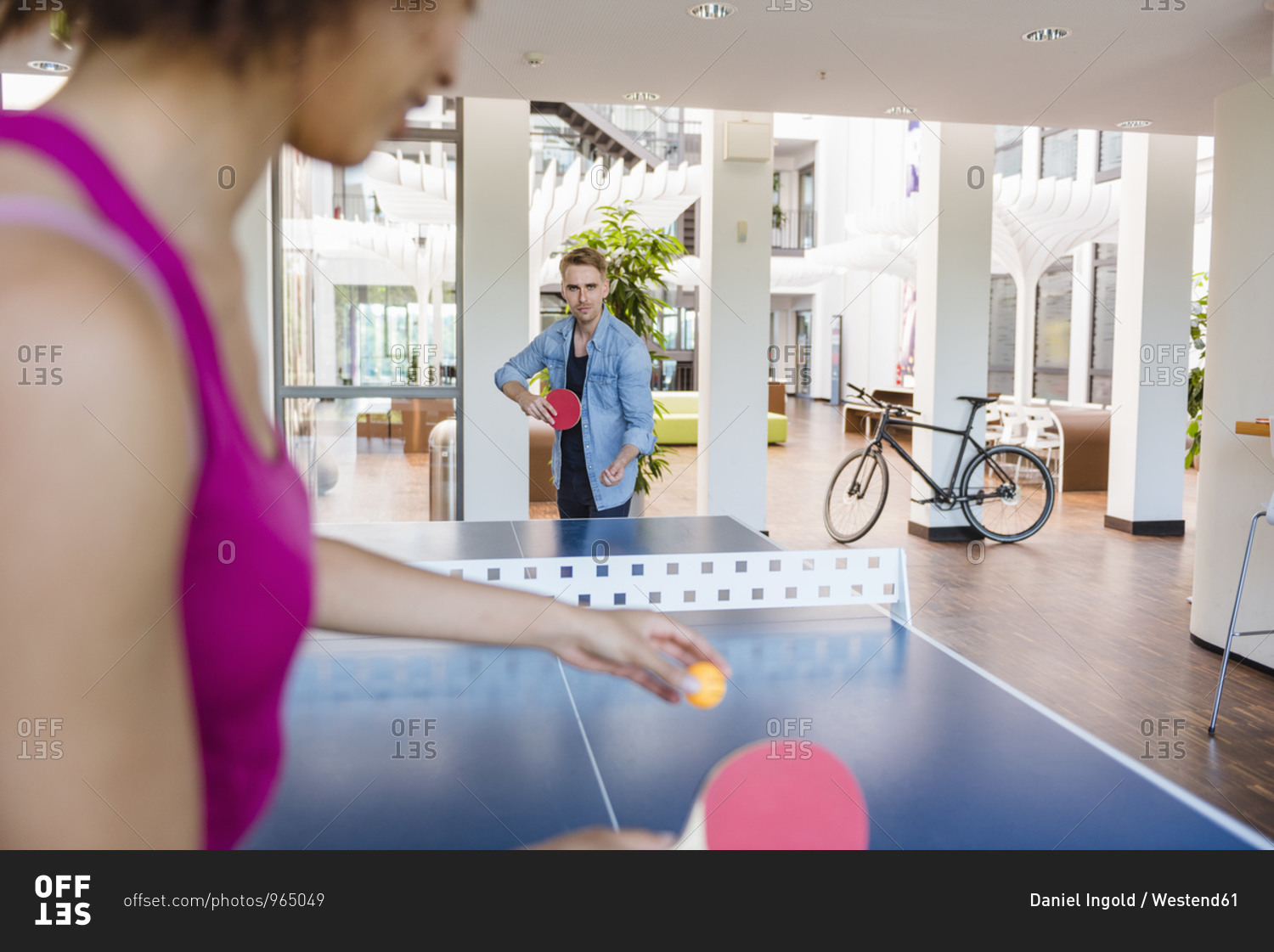 Young business people playing table tennis in loft office