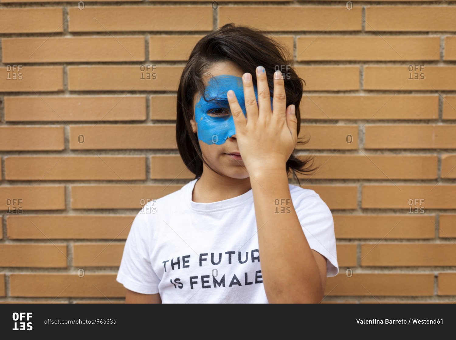 Portrait of boy with painted blue mask on his face wearing t-shirt with imprint \'The Future is Female\'