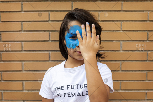 Portrait of boy with painted blue mask on his face wearing t-shirt with imprint 'The Future is Female'