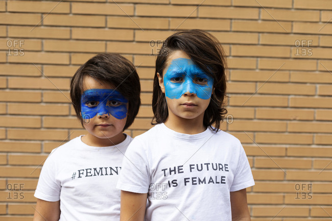 Portrait of two brothers with painted blue masks on their faces wearing t-shirts with feministic imprints