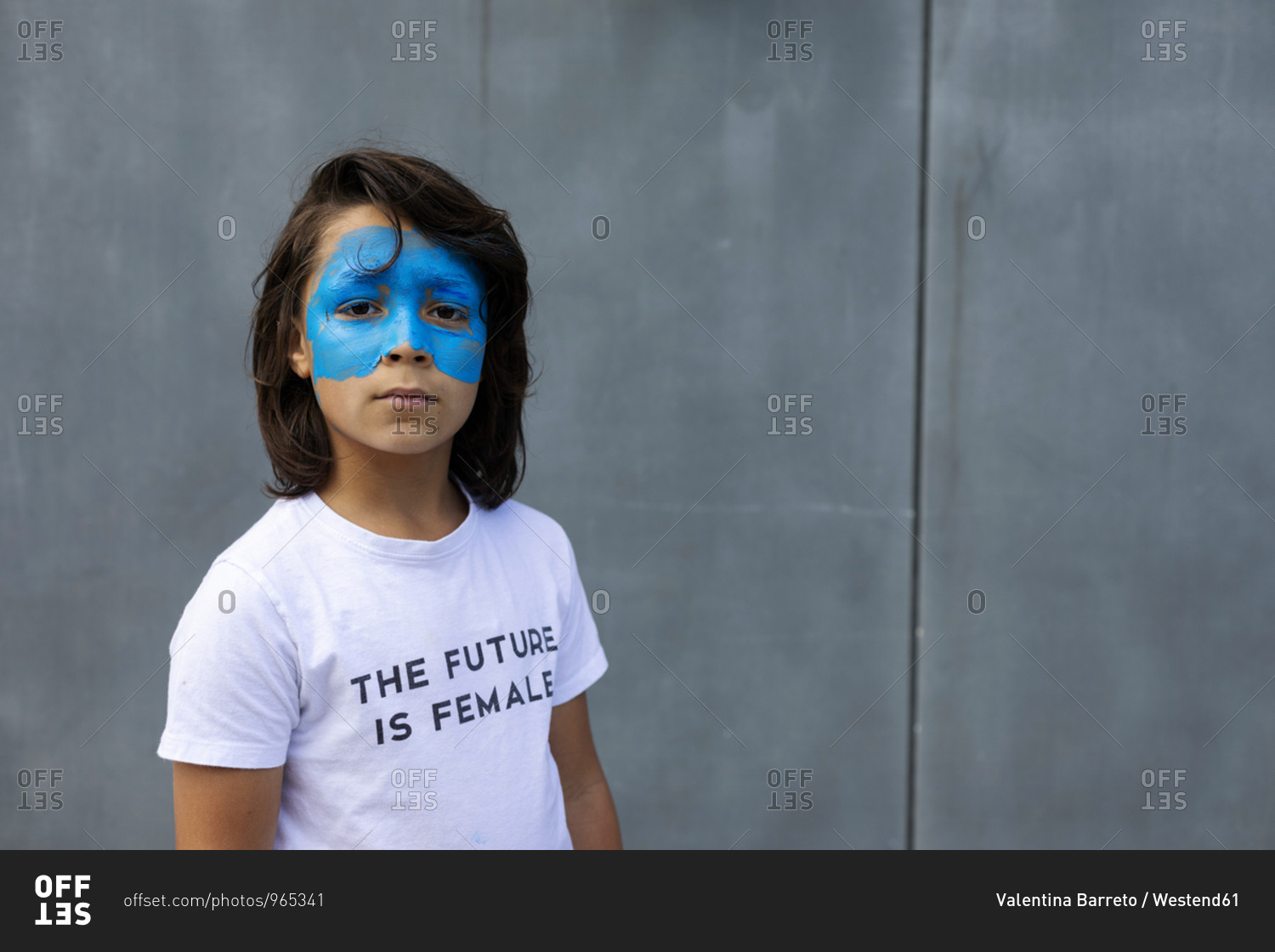 Portrait of boy with painted blue mask on his face wearing t-shirt with imprint \'The Future is Female\'