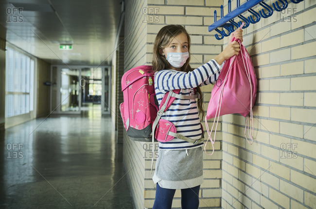 Girl wearing mask in school hanging up pouch