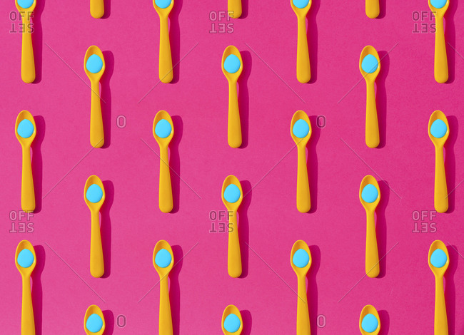 Seamless pattern of yellow plastic teaspoons with blue liquid