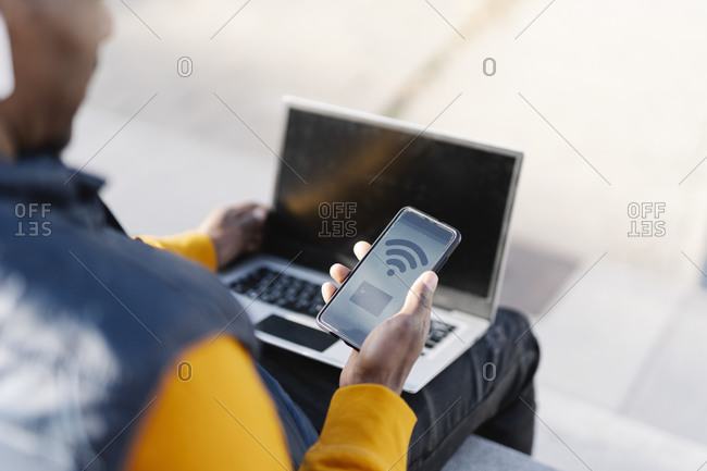 Close-up of man using laptop and smartphone for online shopping