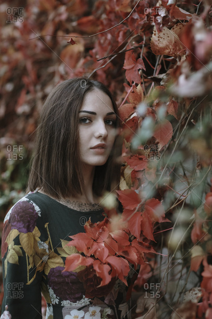 Young woman standing by ivy wall during autumn in park