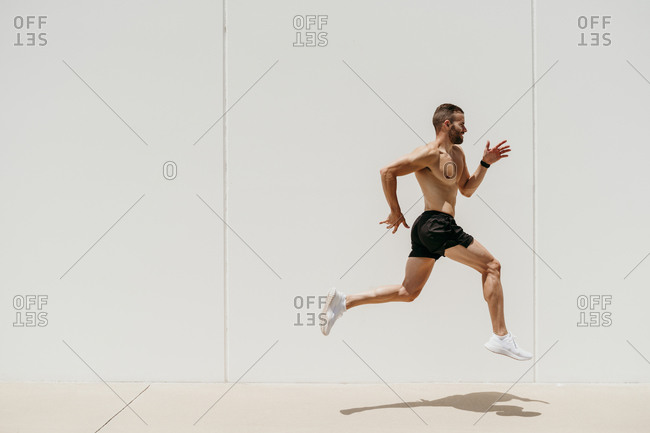 Bare-chested male athlete jumping at a wall