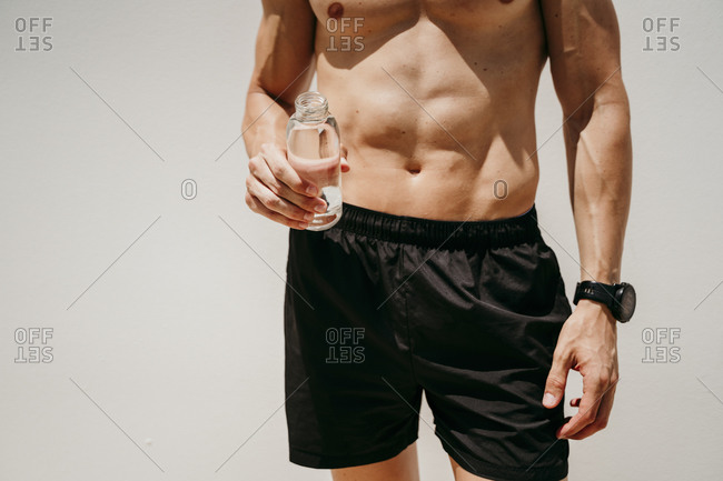 Bare-chested male athlete holding a bottle of water