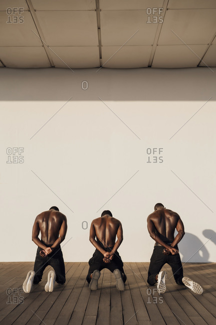 Three man crossing hands behind their backs- kneeling on planks