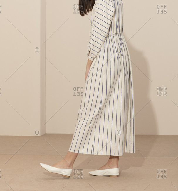 Side vie of a model wearing a blue and white striped casual dress