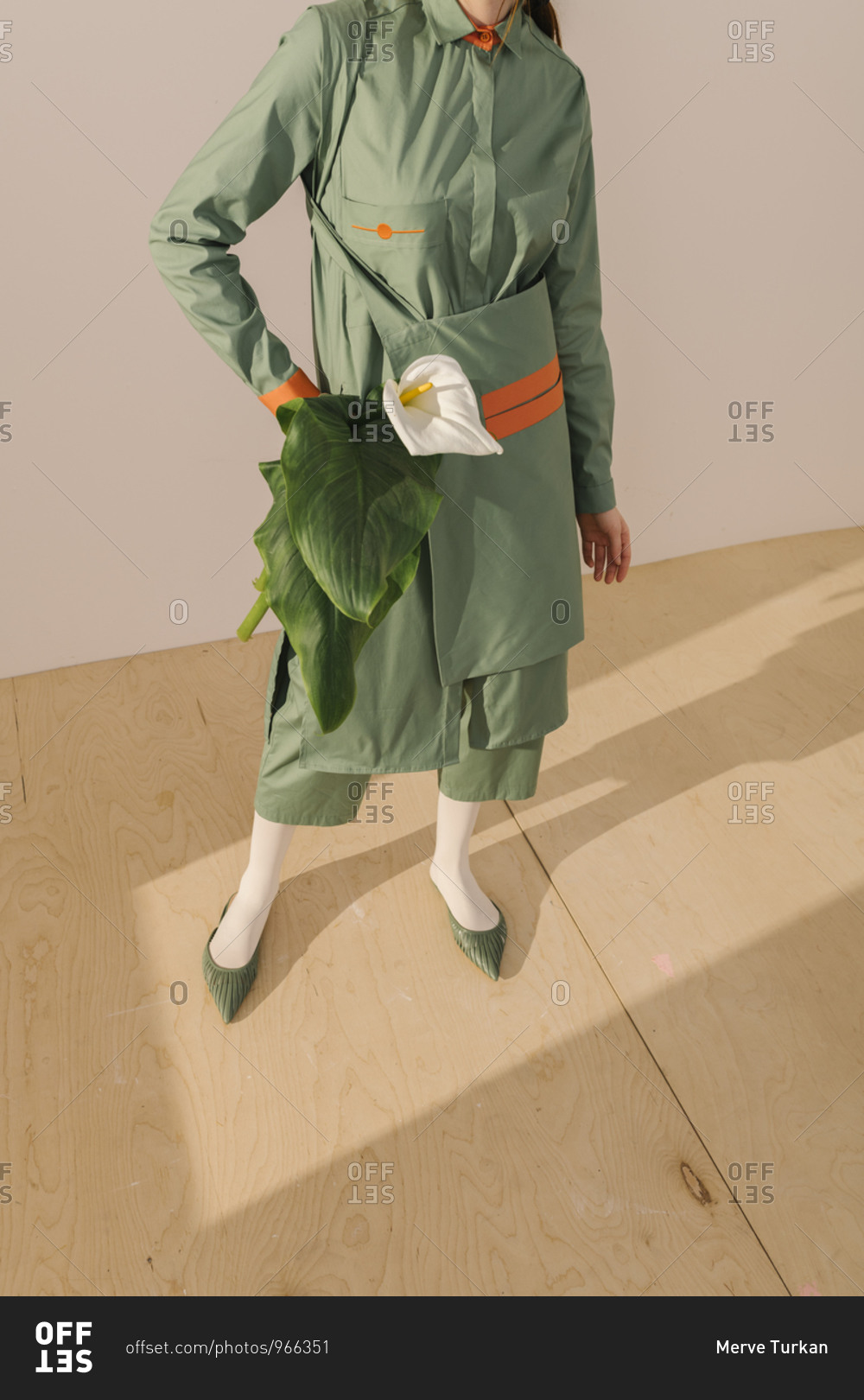 Model Dressed In A Light Green Outfit With Orange Detail Holding A White Calla Lily Stock Photo Offset
