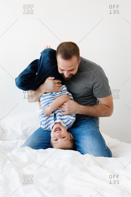 Playful father holding smiling boy upside down