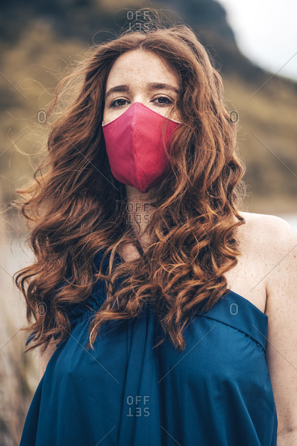 Ginger young woman on the lake with a pink facemask