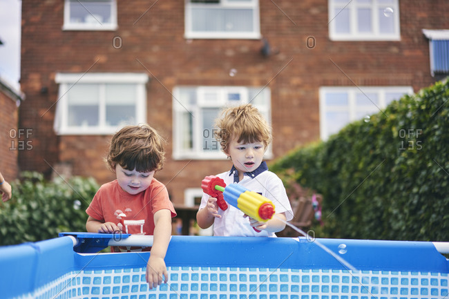 Boys playing with water gun by pool
