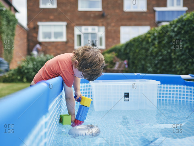 Boy filling up water gun from pool water