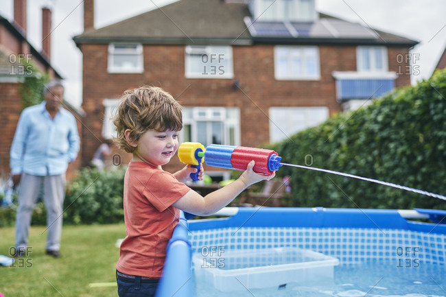 Boy playing with water gun by pool